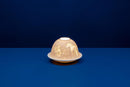 A white, unglazed chinese porcelain tealight candle holder with a dome cover, featuring a lithophane design that becomes visible when backlit.